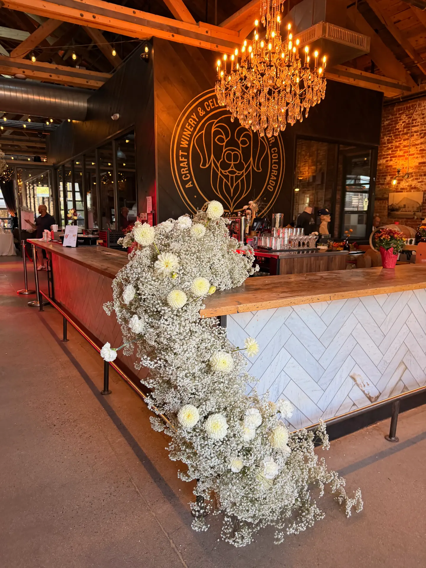 A cascade of white flowers at the bar beneath a chandelier