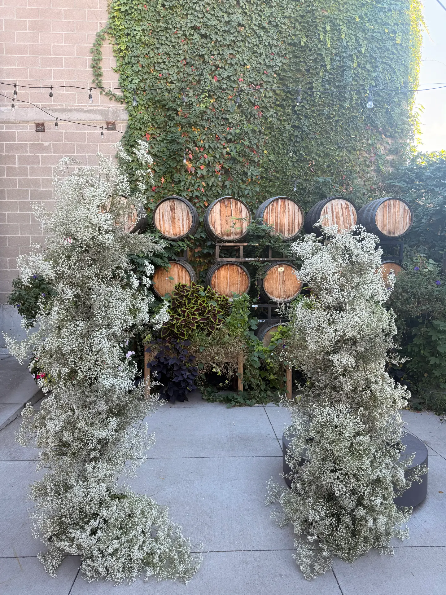 A floral ceremony arch before the barrel wall on the patio