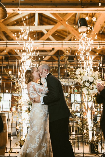 Newlyweds sharing their first kiss beneath crystal chandeliers and white florals