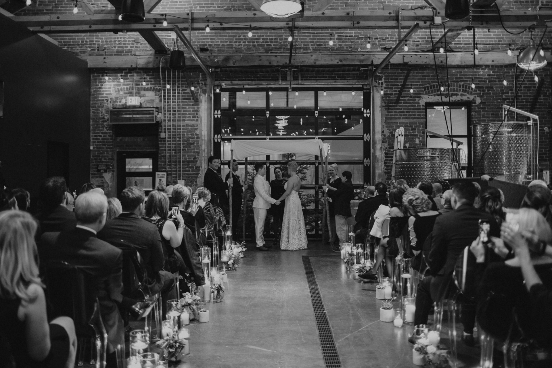 A couple exchanging vows beneath a canopy in the candlelit hall