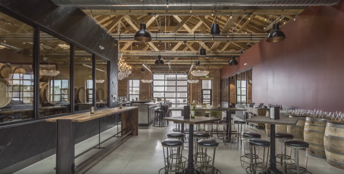 The tasting room with timber trusses, crystal chandeliers, barrel tables and the barrel room behind glass
